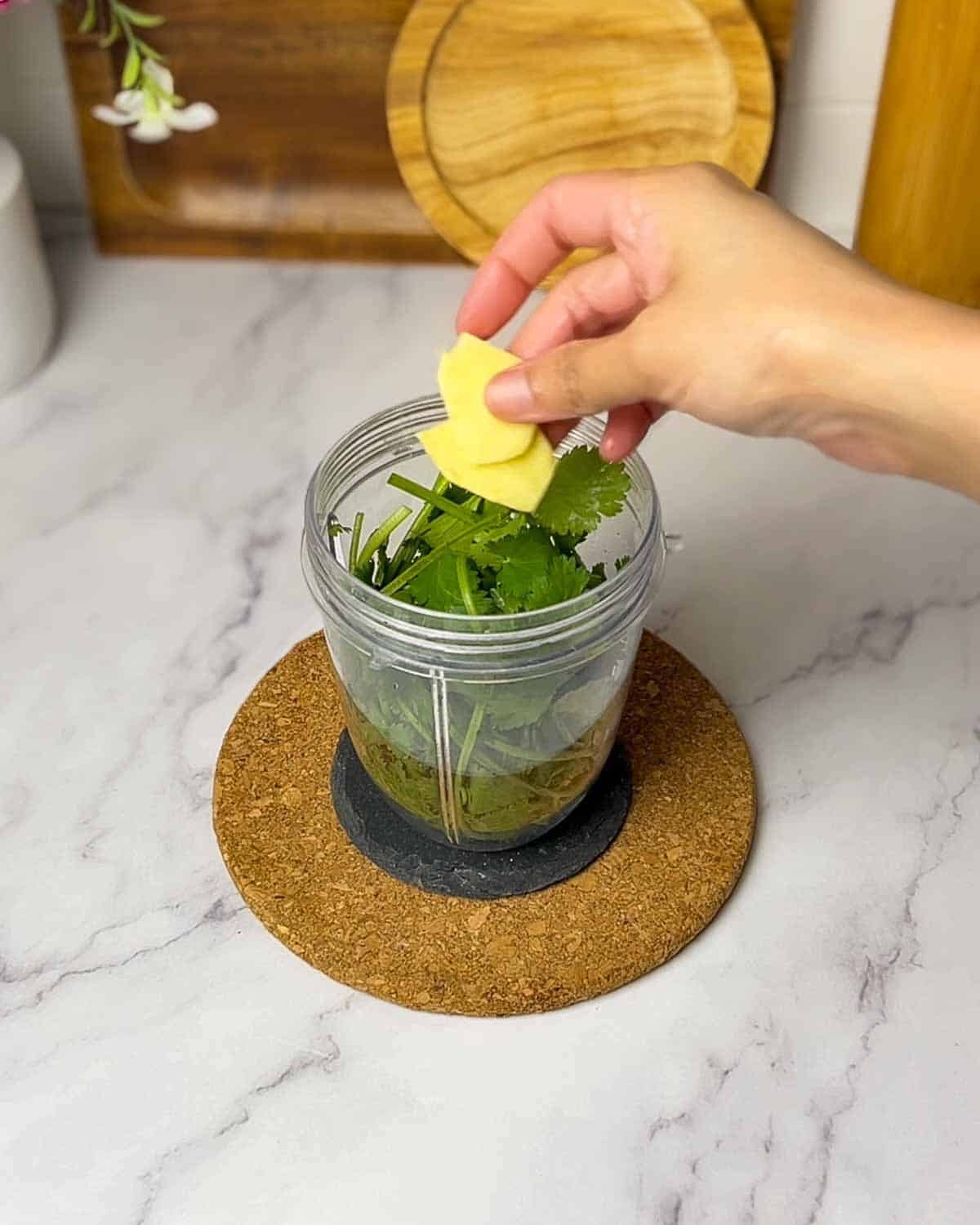 adding cilantro, ginger and seasonings to the blender jar