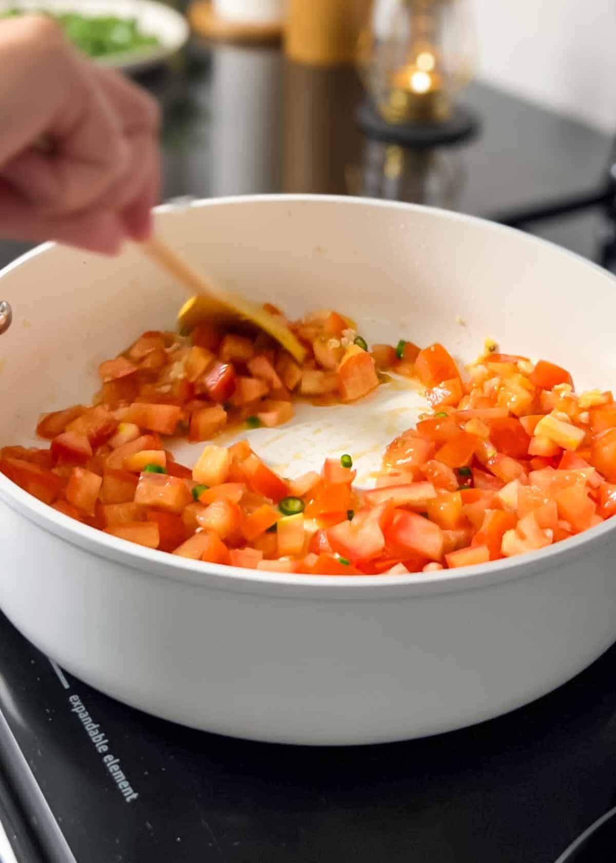 sautéing together tomatoes, garlic and chilies