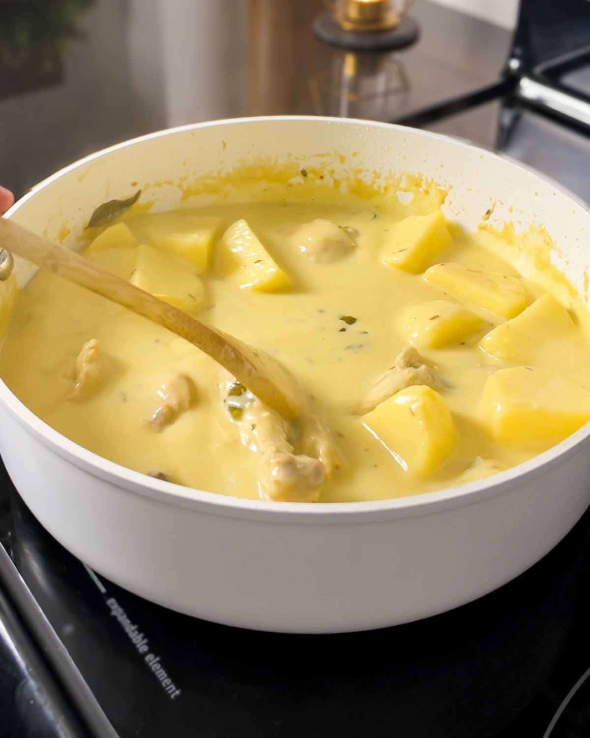 mixing boiled potatoes into the curry