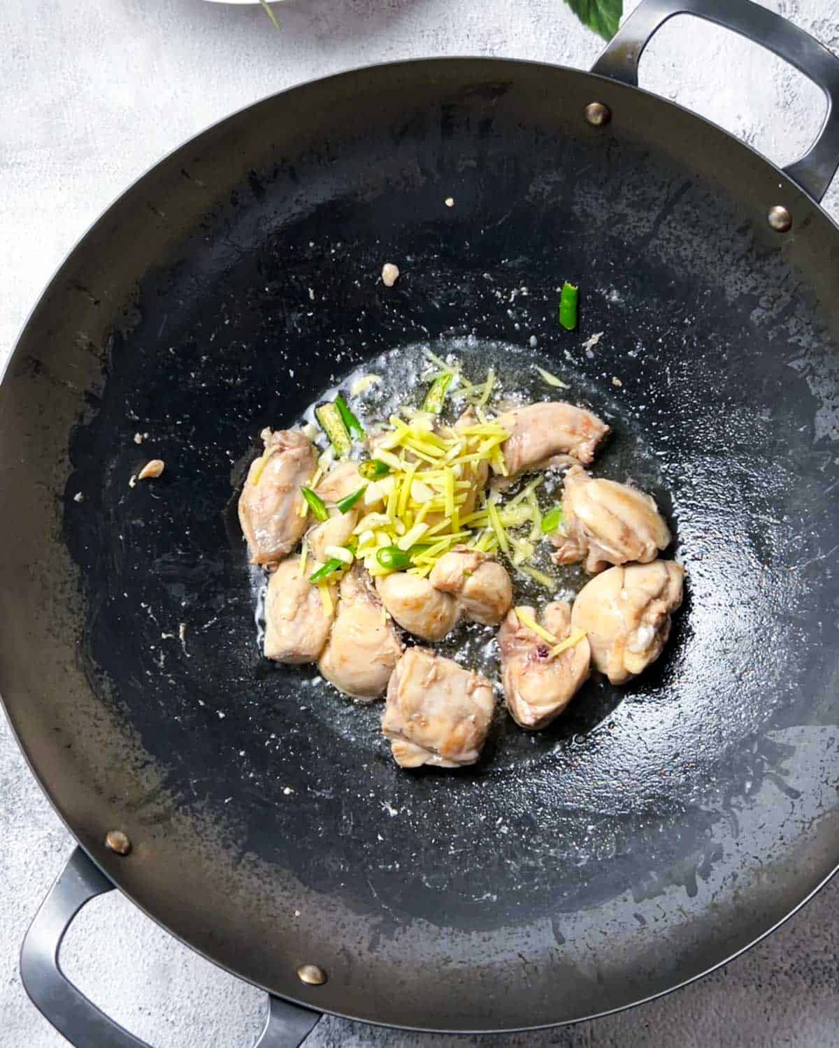 adding ginger, garlic and green chilies to the cooked chicken