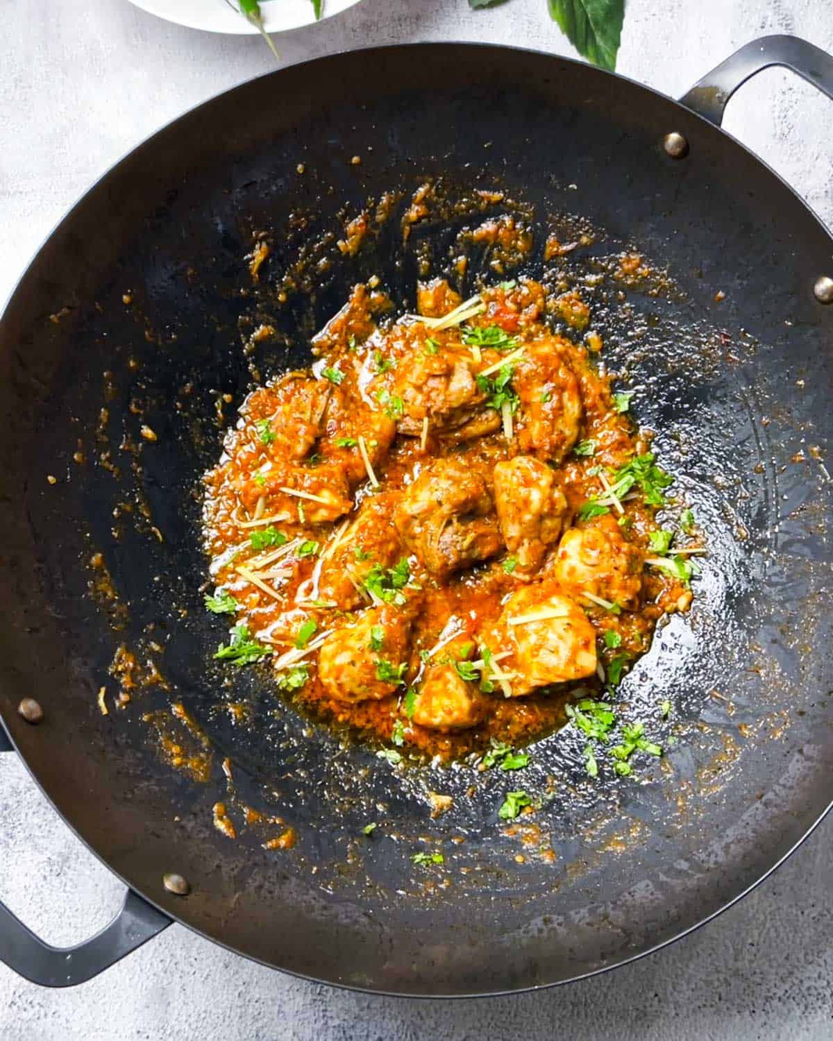 topping cooked karahi with ginger, cilantro and lemon juice