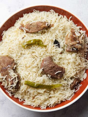 beef pulao on a plate topped with cooked chilies