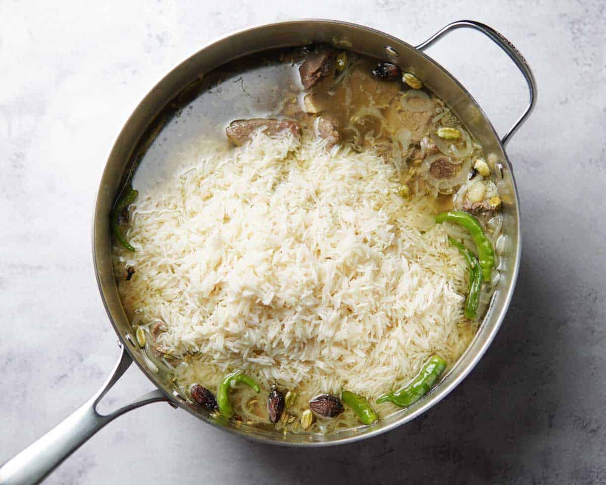 beef, rice, aromatics, and broth in a large pan