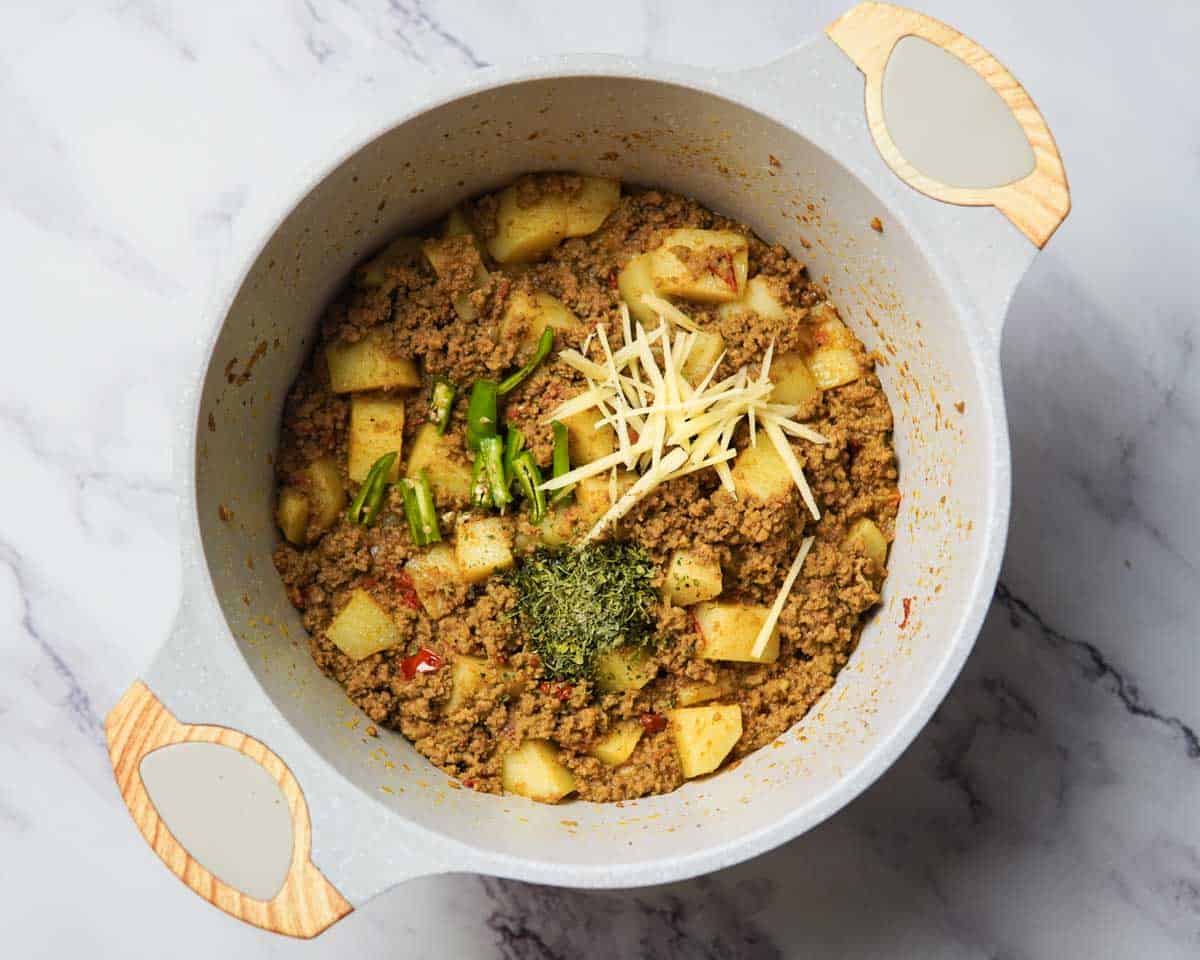 adding chilies, ginger and dried methi leaves to the keema