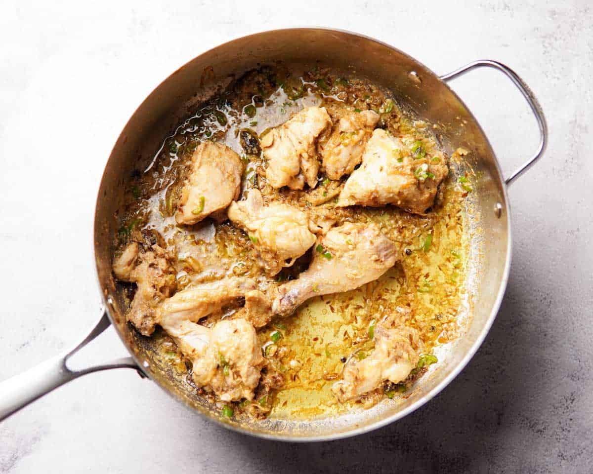 chicken cooked in spices, yogurt and onion sitting in a pan
