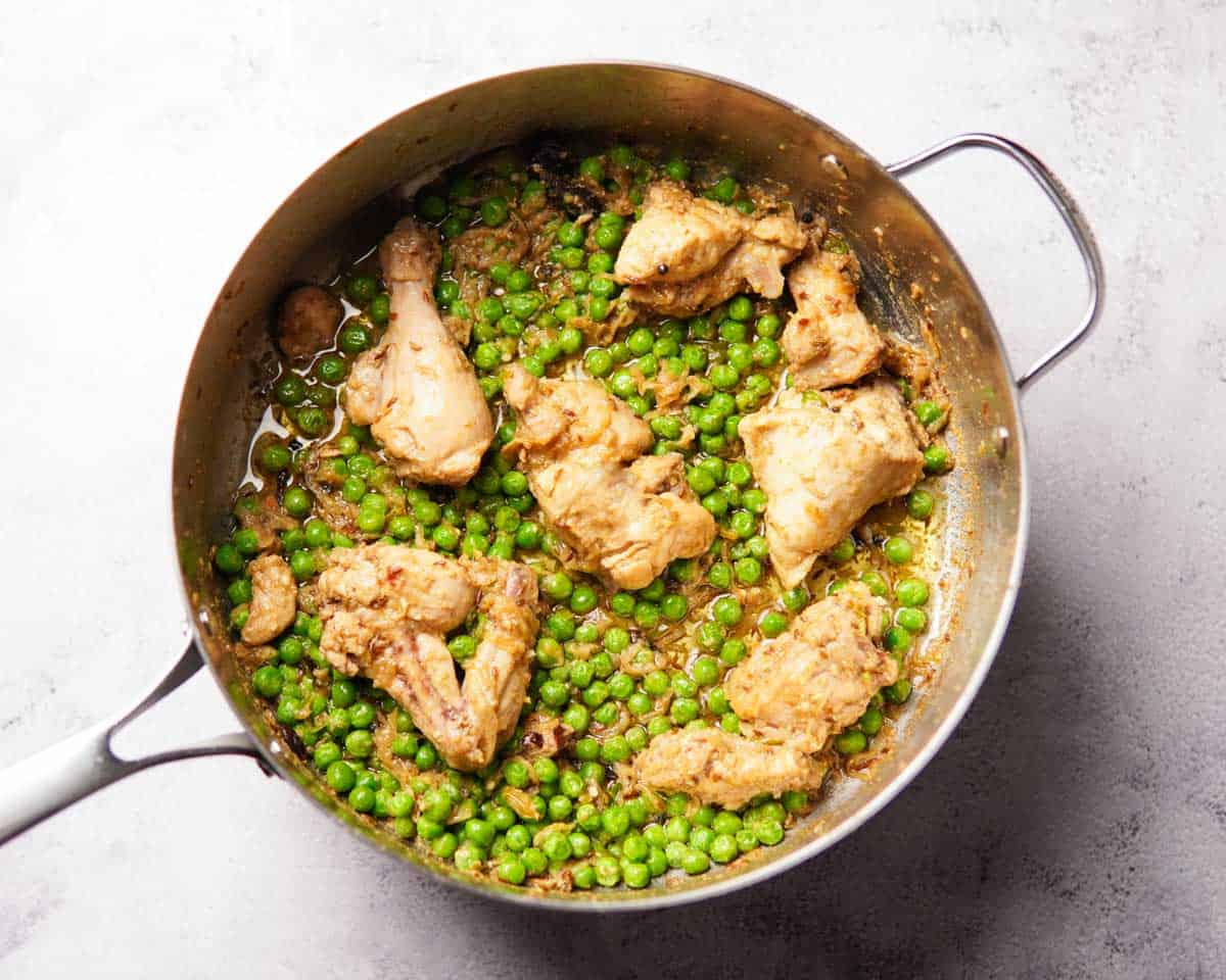 delicious looking cooked chicken with green peas in a pan