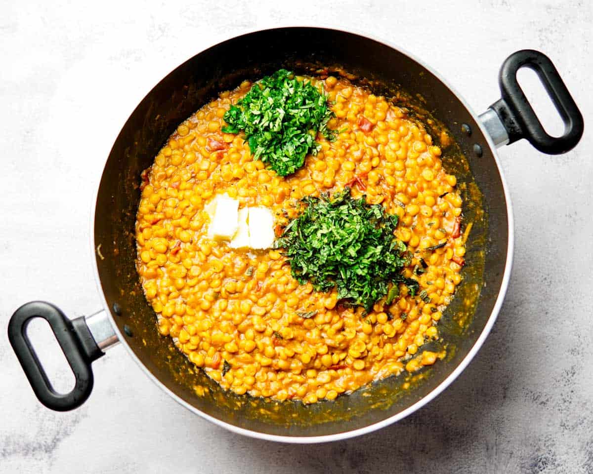 chana dal with chopped cilantro, mint and butter cooking in a pan