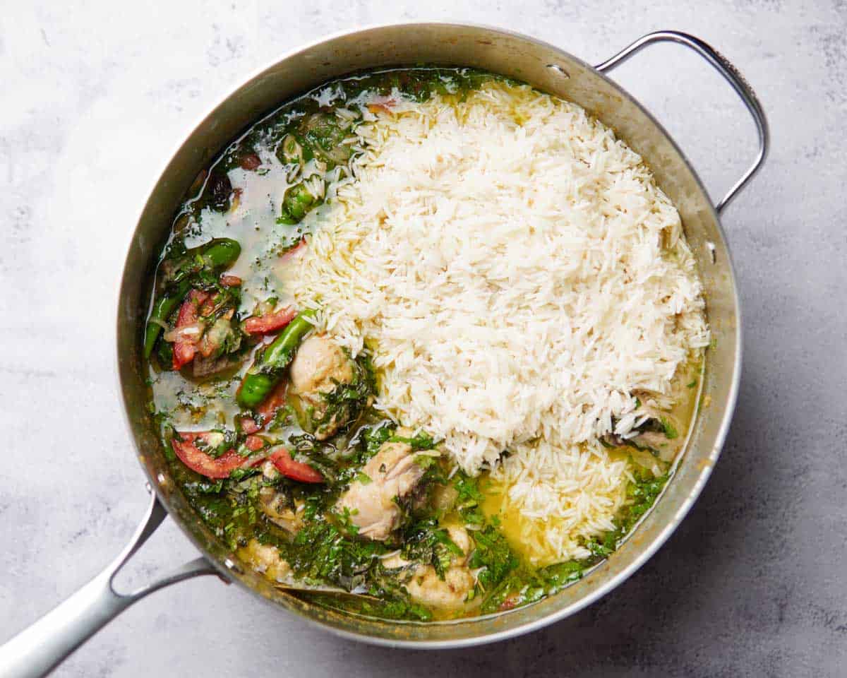 rice, chicken, herbs and broth in a pan