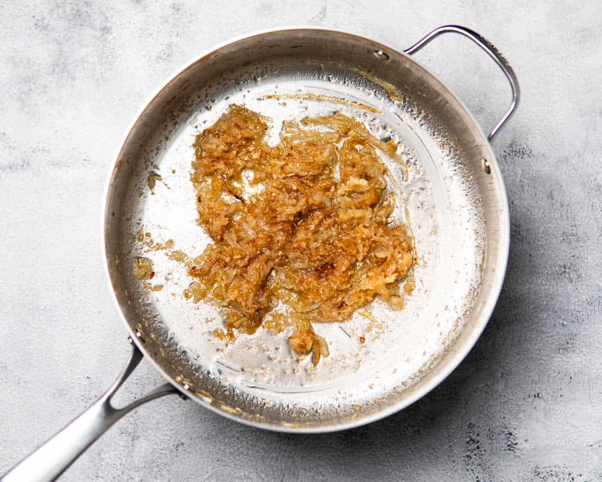 a cooking pan that has onions caramelizing along with aromatics
