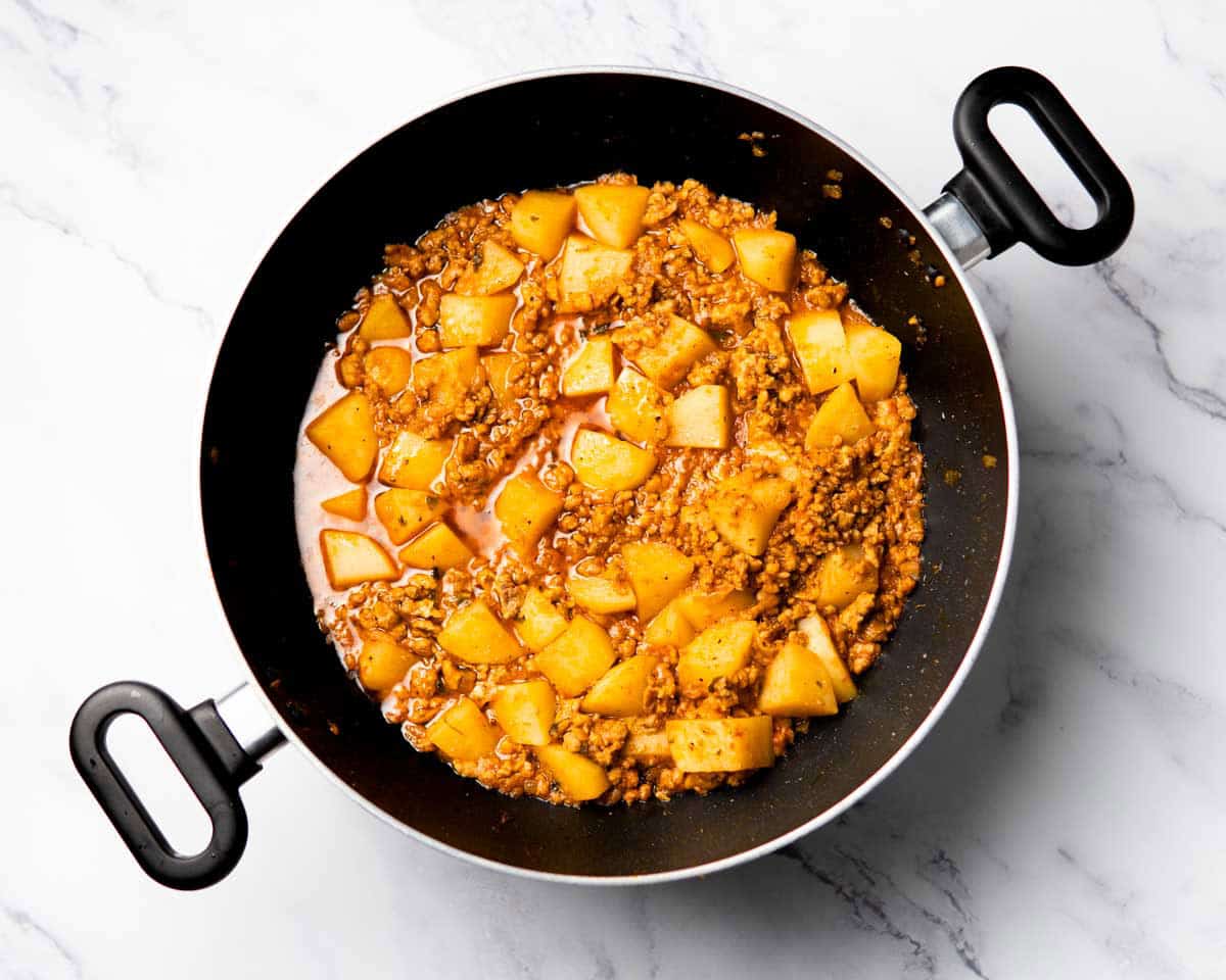 chicken mince and potatoes cooking in a spiced tomato base