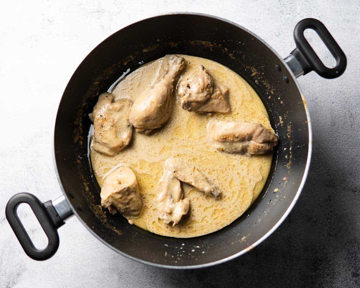 chicken cooking in creamy white sauce in a wok