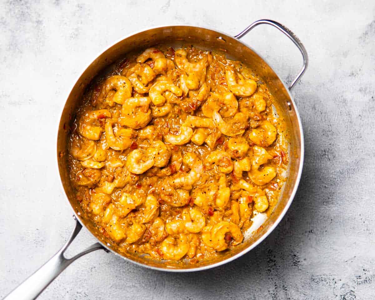 a pan containing shrimp that's cooking in a spiced yogurt base