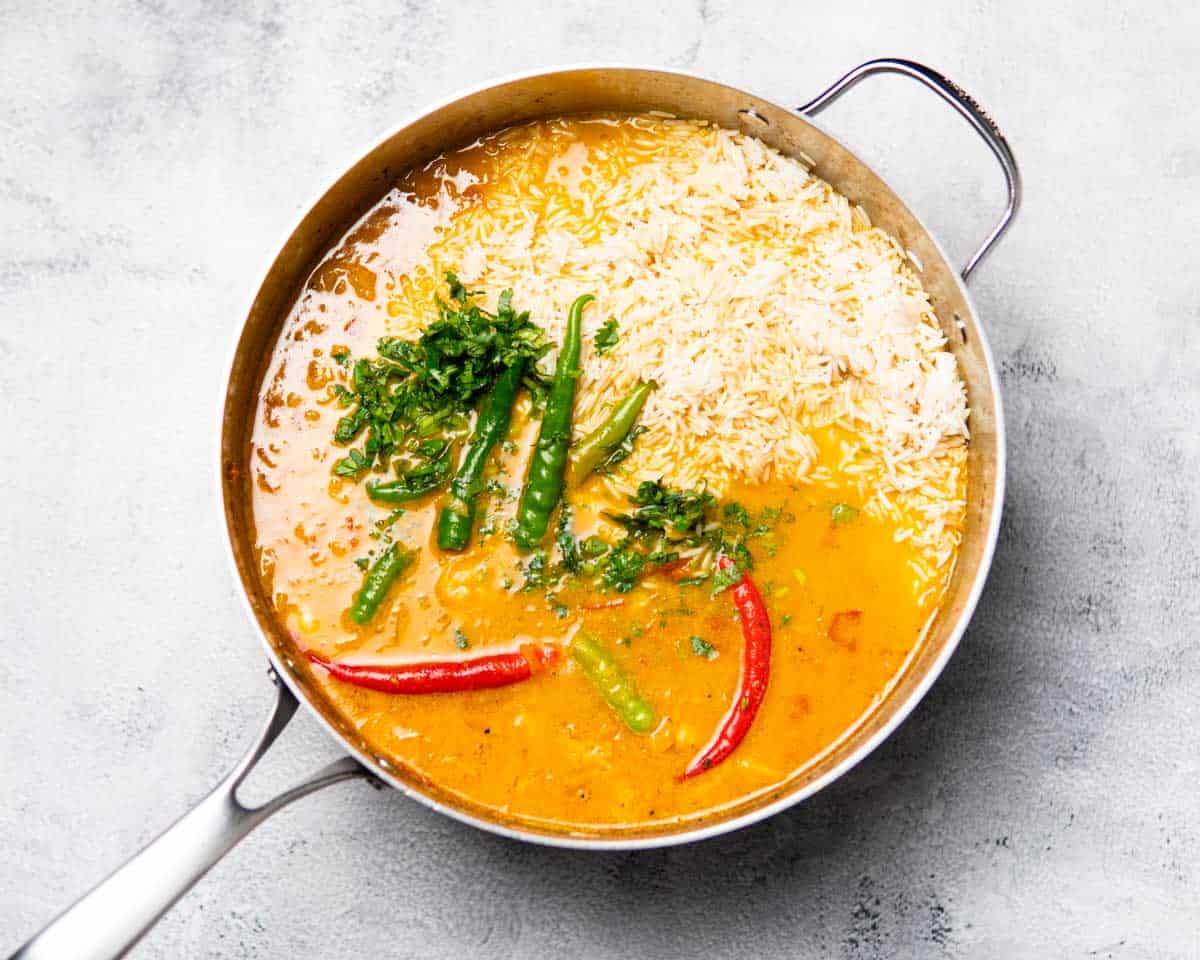Pan filled with shrimp, rice in a broth that has cilantro and chilies